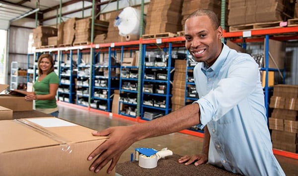 Happy Man In Warehouse With Box Women In Background